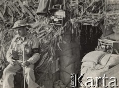 Wiosna 1944, Cassino, Włochy.
Bitwa pod Monte Cassino. Żołnierz siedzący przed schronem przykrytym siatką maskującą. Przy wejściu do schronu stoją dwa radiotelefony.
Fot. NN, zbiory Instytutu Józefa Piłsudskiego w Londynie

