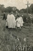 Prawdopodobnie 1943-1947, Kidugala, Tanganika.
Ksiądz z ministrantami.
Fot. ze zbiorów Archiwum Ojców Franciszkanów w Polskiej Misji Katolickiej w Martin Coronado w Argentynie, akta ojca Justyniana Maciaszka, reprodukcje cyfrowe w  Bibliotece Polskiej im. Ignacego Domeyki w Buenos Aires (Biblioteca Polaca Ignacio Domeyko) i w Ośrodku KARTA w Warszawie