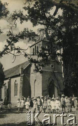 1943-1947, Kidugala, Tanganika.
Przed kościołem.
Fot. ze zbiorów Archiwum Ojców Franciszkanów w Polskiej Misji Katolickiej w Martin Coronado w Argentynie, akta ojca Justyniana Maciaszka, reprodukcje cyfrowe w  Bibliotece Polskiej im. Ignacego Domeyki w Buenos Aires (Biblioteca Polaca Ignacio Domeyko) i w Ośrodku KARTA w Warszawie