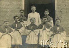 1943-1947, Kidugala, Tanganika.
Ojciec Justynian Maciaszek (1913-1959, proboszcz parafii w Kidugali, współtwórca ośrodka polskiego duszpasterstwa w argentyńskim Martin Coronado) z ministrantami.
Fot. ze zbiorów Archiwum Ojców Franciszkanów w Polskiej Misji Katolickiej w Martin Coronado w Argentynie, akta ojca Justyniana Maciaszka, reprodukcje cyfrowe w  Bibliotece Polskiej im. Ignacego Domeyki w Buenos Aires (Biblioteca Polaca Ignacio Domeyko) i w Ośrodku KARTA w Warszawie