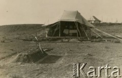 1942-1943, Bliski Wschód.
Polski obóz wojskowy, w namiocie stoi ołtarz, przed nim grób.
Fot. NN, zbiory Krzysztofa Barbarskiego, reprodukcje cyfrowe w Ośrodku KARTA w Warszawie i w Instytucie Polskim i Muzeum im. gen. Sikorskiego w Londynie.