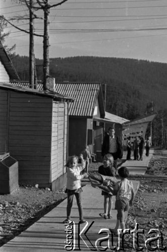 Lata 70., Tynda, obwód amurski, Rosyjska Federacyjna Socjalistyczna Republika Radziecka, ZSRR.
Budowa Bajkalsko-Amurskiej Magistrali Kolejowej. Życie codzienne na osiedlu nowych drewnianych domów, wznoszonych w związku z rozwojem miasta i budową iniii kolejowej - bawiące się dzieci.
Fot. Mikołaj Nesterowicz, zbiory Ośrodka KARTA
