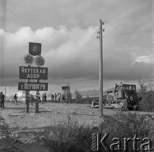 1977, Nieriungri, Jakucka Autonomiczna Socjalistyczna Republika Radziecka, Rosyjska Federacyjna Socjalistyczna Republika Radziecka, ZSRR.
Budowa Bajkalsko-Amurskiej Magistrali Kolejowej (BAM). Maszyny do prac ziemnych pracują przy stojącej przy wjeździe do miasta tablicy informującej o przynależności administracyjnej terenu.
Fot. Mikołaj Nesterowicz, zbiory Ośrodka KARTA