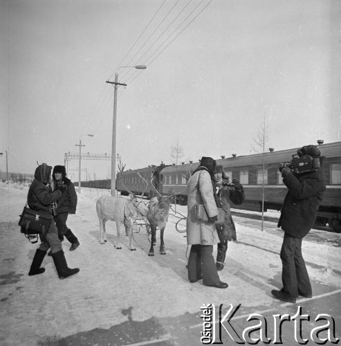 1977, prawdopodobnie Berkakit, Jakucka Autonomiczna Socjalistyczna Republika Radziecka, ZSRR.
Budowa Kolei Amursko-Jakuckiej na odcinku między Tyndą a Berkakit, zwanym Małym BAM (Małą Bajkalsko-Amurską Magistralą Kolejową). Dziennikarze rozmawiają z mężczyzna z ludu Sacha, który przyprowadził renifery na peron nowo otwartej stacji.
Fot. Mikołaj Nesterowicz, zbiory Ośrodka KARTA