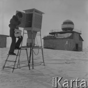Lata 70., Biegun Północny.
Stacja badawcza. Mężczyzna wyjmuje z klatki meteorologicznej przyrządy pomiarowe.
Fot. Mikołaj Nesterowicz, zbiory Ośrodka KARTA
