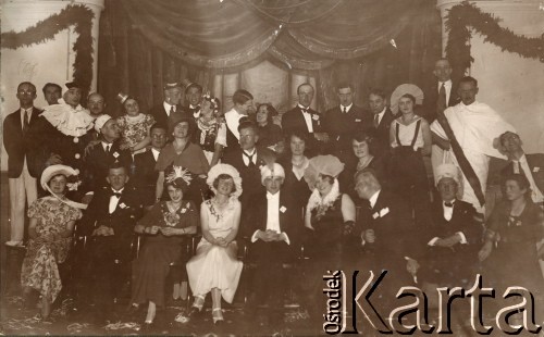 1933, Solec-Zdrój, woj. kieleckie, Polska.
Bal kostiumowy zorganizowany u Zofii i Andrzeja Dzianottów, rodziców Barbary Murzynowskiej. W pierwszym rzędzie 3. z lewej siedzi Anna Zgłuska (właścicielka apteki w Solcu), 4. Maria Łaszkiewicz ze Zborowa, 5. Andrzej Dzianott (ojciec Barbary, później po mężu Murzynowskiej). W drugim rzędzie 1. z prawej siedzi Rożniakowska. W ostatnim rzędzie 7. z lewej stoi Lucjan Czechowski, 9. Władysław Daniewski (wuj Barbary Murzynowskiej).
Fot. NN, kolekcja Barbary Murzynowskiej, reprodukcje cyfrowe w Ośrodku KARTA