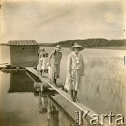 Ok. 1918, Polska.
Dwór Plater-Zyberk. Rodzina podczas spaceru nad jeziorem. Na kładce 1. z prawej stoi prawdopodobnie Antonina Plater-Zyberk z d. Kalkstein, 4. jej córka Wanda, później po mężu Murzynowska, matka Jana, męża Barbary Murzynowskiej).
Fot. NN, kolekcja Barbary Murzynowskiej, reprodukcje cyfrowe w Ośrodku KARTA