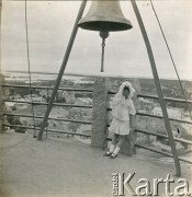 1918-1920, brak miejsca.
Wanda Plater-Zyberk (córka Antoniny i Henryka Michała hr. z Broelu, później matka Jana Murzynowskiego, męża Barbary Murzynowskiej) stoi pod dzwonem. 
Fot. NN, kolekcja Barbary Murzynowskiej, reprodukcje cyfrowe w Ośrodku KARTA