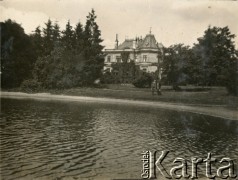 Lata 30., Polska.
Mężczyźni stoją nad brzegiem stawu. W głębi między drzewami widać majątek dworski.
Fot. NN, kolekcja Barbary Murzynowskiej, reprodukcje cyfrowe w Ośrodku KARTA
