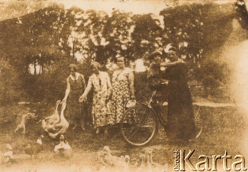 1935, Oszmiana, woj. wileńskie, Polska. 
Rodzina Luro przed domem. 3. z lewej matka Jadwiga Luro (karmi gęsi). Na rowerze siedzi Waleria Luro (później Sawicka), obok niej stoi ksiądz Józef Król.
Fot. NN, kolekcja Walerii Sawickiej, reprodukcje cyfrowe w Ośrodku KARTA