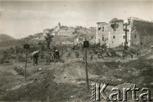 1944-1945, okolice Cassino, Włochy.
Żołnierze 2 Korpusu Polskiego Polskich Sił Zbrojnych na Zachodzie na cmentarzu polowym. W głębi widoczne zbombardowane miasteczko. 
Fot. NN, kolekcja: Polska Misja Katolicka, reprodukcje cyfrowe w Ośrodku KARTA