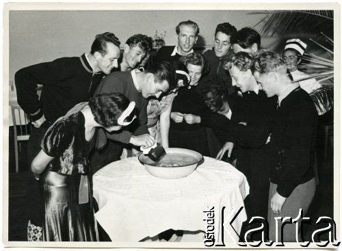 1954, Zakopane, woj. krakowskie, Polska Rzeczpospolita Ludowa.
Bal olimpijczyków - jedna z gier podczas zabawy. Uczestnicy zgromadzeni wokół stołu. Widoczni skoczkowie narciarscy.
Fot. Stefan Burnatowicz, kolekcja Stefana Burnatowicza, zbiory Ośrodka KARTA