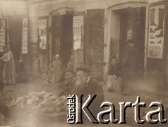1900-1920, miejsce nieznane.
Bazar na placu miejskim. Na pierwszym planie kobieta i mężczyzna w podeszłym wieku sprzedają pieczywo. W tle szyldy z polskimi i rosyjskimi napisami.
Fot. NN, kolekcja rodziny Walińskich, zbiory Fundacji Ośrodka KARTA