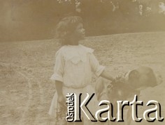 1900-1920, miejsce nieznane.
Prawdopodobnie córka Jadiwgi i Czesława Walińskich. Dziewczynka trzyma zebrane kwiaty i psa za obrożę. W tle drzewa.
Fot. NN, kolekcja rodziny Walińskich, zbiory Fundacji Ośrodka KARTA