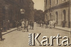 1900-1920, miejsce nieznane.
Ulica w mieście. Po dwóch stronach kamienice. W oddali widać drzewa. Na deptaku konie i dwóch mężczyzn. Na chodnikach ludzie.
Fot. NN, kolekcja rodziny Walińskich, zbiory Fundacji Ośrodka KARTA