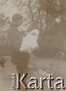 1920-1930, miejsce nieznane, Polska.
Mężczyzna. Trzyma na rękach dziecko. Obok stoi wózek. W oddali widać drzewa.
Fot. NN, kolekcja rodziny Walińskich, zbiory Fundacji Ośrodka KARTA
