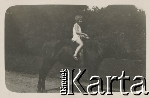 1920-1930, miejsce nieznane, Polska.
Dziewczynka na koniu. W tle łąka i drzewa.
Fot. NN, kolekcja rodziny Walińskich, zbiory Fundacji Ośrodka KARTA
