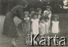 1930-1940, miejsce nieznane, Polska.
Kobieta ustawia dzieci do zdjęcia.
Fot. NN, kolekcja rodziny Walińskich, zbiory Fundacji Ośrodka KARTA