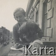 1930-1940, miejsce nieznane, Polska.
Kobieta i dziewczynka na balkonie. Dziewczynka pisze coś w notatniku.
Fot. NN, kolekcja rodziny Walińskich, zbiory Fundacji Ośrodka KARTA