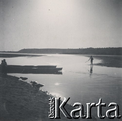1930-1940, miejsce nieznane, Polska.
Krajobraz. Brzegiem jeziora spaceruje dziecko. Przy kajakach pozostałe osoby.
Fot. NN, kolekcja rodziny Walińskich, zbiory Fundacji Ośrodka KARTA