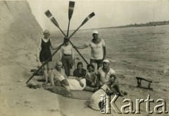 Lata 20., Rzeczpospolita Polska.
Grupa osób odpoczywająca na plaży nad jeziorem.
Fot. NN, kolekcja Larysy Zajączkowskiej-Mitznerowej, zbiory Ośrodka KARTA