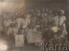 1942, Gurlen, Uzbekistan, ZSRR
Próba powołania do życia polskiej szkoły, Bolesław Godowski trzyma portret gen. Sikorskiego, Alicja Godowska stoi w ostatnim rzędzie trzecia od lewej (z kokardą pod szyją), w środku siedzi por. Jan Pisarek polski delegat na rejon Gurlen, obok niego nauczycielki, Sarnacka i Jantecka; po ulokowaniu rodzin w kołchozach w promieniu 15 km od Gurlen nie było komu chodzić do szkoły.
Fot. NN, zbiory Ośrodka KARTA, udostępniła Alicja Dymecka.