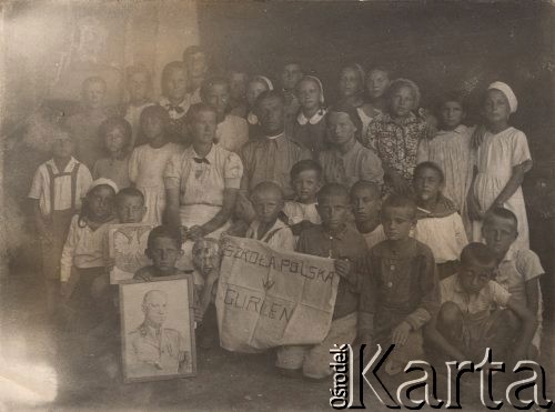 1942, Gurlen, Uzbekistan, ZSRR
Próba powołania do życia polskiej szkoły, Bolesław Godowski trzyma portret gen. Sikorskiego, Alicja Godowska stoi w ostatnim rzędzie trzecia od lewej (z kokardą pod szyją), w środku siedzi por. Jan Pisarek polski delegat na rejon Gurlen, obok niego nauczycielki, Sarnacka i Jantecka; po ulokowaniu rodzin w kołchozach w promieniu 15 km od Gurlen nie było komu chodzić do szkoły.
Fot. NN, zbiory Ośrodka KARTA, udostępniła Alicja Dymecka.