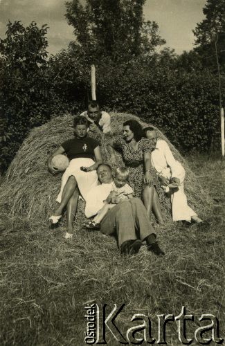 1940, Rumunia.
Polscy uchodźcy w Rumunii podczas II wojny światowej - grupa osób w letnich ubraniach siedzi na sianie, z przodu mężczyzna z dzieckiem na kolanach, na górze leży Tadeusz Krajewski.
Fot. NNH, zbiory Ośodka KARTA, udostępnił Adam Krajewski.