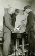 1940, Targu-Jiu, Rumunia
Obóz internowania dla żołnierzy Wojska Polskiego, wydawanie obiadu; stoją od prawej: podporucznik w mundurze polowym wz. 36 i w rogatywce polowej wz. 37 - oficer ten chochlą nalewa z garnka zupę, z tyłu siedzi kpt. pilot Tadeusz Krajewski, w środku stoi porucznik w mundurze - płaszczu polowym wz. 36 i w rogatywce polowej wz. 37, z lewej podporucznik w mundurze polowym wz. 36. Na odwrocie pieczątka Oflag VI/B Geprüft 7a.
Fot. NN, zbiory Ośrodka Karta, album (A-XII), udostępnił A. Krajewski.

[II wojna światowa, lata 40-te, Polacy w Rumunii, Targu Jiu, obóz internowania dla żołnierzy WP, Wojsko Polskie, obozy, internowanie, jeńcy, internowani, żołnierze, oficerowie, lotnictwo, lotnicy, lotnik, piloci, pilot, jedzenie, wyżywienie, zupa]