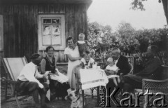 1920-1939, Lebiodka, powiat Lida, woj. Nowogródek, Polska.
Rodzina Sopoćków przed domem, siedzą od lewej: kazimierz Sopoćko (kapitan rezerwy), ciocia Tania (żona Czesława), Anna Sopoćko z córką Reginą, oparty o stół Michał Sopoćko (syn Tani i Czesława), Romuald Sopoćko (doktor medycyny z Lidy) z Haliną Sopoćko na kolanach, czesław Sopoćko (kapitan artylerii w służbie czynnej z Grodna), w głębi ogród kwiatowy ze szpalerem bzów.
Fot. NN, zbiory Ośrodka KARTA, udostępniła Halina Grecka.