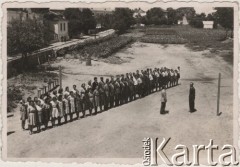 Lata 40., Craiova, Rumunia.
Polscy uchodźcy w Rumunii podczas II wojny światowej. Poranny apel Szkoły Polskiej w Craiovej. Dyrektor szkoły Teofil Matkowski przyjmuje raport Zdzisława Bieńka.
Fot. NN, zbiory Ośrodka KARTA, udostępnił Tadeusz Gaydamowicz.