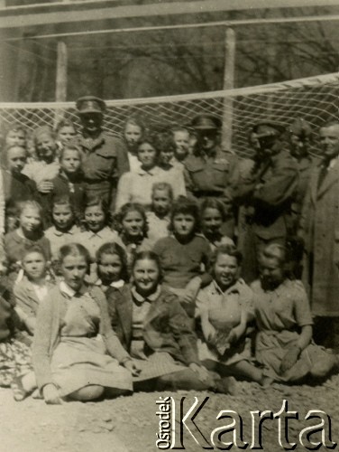 1943, Teheran, Iran.
Dzieci i ich opiekunowie z obozu dla Polaków ewakuowanych z ZSRR (Nr 2). [Polscy uchodźcy trafili do Iranu w 1942 wraz z nowoutworzonym Wojskiem Polskim pod dowództwem generała Władysława Andersa (w dwóch rzutach ewakuacyjnych z ZSRR w marcu i sierpniu). W sumie oprócz wojska dotarło tam 38 tysięcy Polaków, z czego ponad połowę stanowiły dzieci i młodzież. W Teheranie powstały trzy obozy dla ludności cywilnej i sierociniec; stąd kierowano Polaków do stałych osiedli w różnych rejonach świata (np. w Nowej Zelandii, Ugandzie, Meksyku)].
Fot. NN, zbiory Ośrodka KARTA, kolekcja Adeli Duszy przekazała Halina Guść