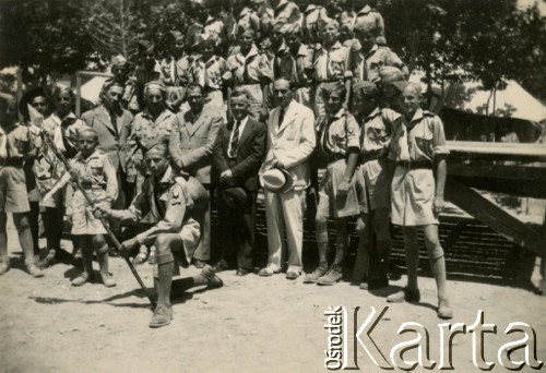 24.06.1943, Teheran, Iran.
Starosta Roman Dusza (w czarnym garniturze) podczas odprawy II Hufca w obozie dla Polaków ewakuowanych z ZSRR (Nr 1). Na zdjęciu również Zdzisław Bąk. [Polscy uchodźcy trafili do Iranu w 1942 wraz z nowoutworzonym Wojskiem Polskim pod dowództwem generała Władysława Andersa (w dwóch rzutach ewakuacyjnych z ZSRR w marcu i sierpniu). W sumie oprócz wojska dotarło tam 38 tysięcy Polaków, z czego ponad połowę stanowiły dzieci i młodzież. W Teheranie powstały trzy obozy dla ludności cywilnej i sierociniec; stąd kierowano Polaków do stałych osiedli w różnych rejonach świata (np. w Nowej Zelandii, Ugandzie, Meksyku)].
Fot. NN, zbiory Ośrodka KARTA, kolekcja Adeli Duszy przekazała Halina Guść