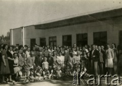 8.05.1944, Isfahan, Iran. 
Fotografia pamiątkowa z imienin kierownika Ekspozytury i Delegatury Ministerstwa Pracy i Opieki Społecznej. [Polscy uchodźcy trafili do Iranu w 1942 wraz z nowoutworzonym Wojskiem Polskim pod dowództwem generała Władysława Andersa (w dwóch rzutach ewakuacyjnych z ZSRR w marcu i sierpniu). W sumie oprócz wojska dotarło tam 38 tysięcy Polaków, z czego ponad połowę stanowiły dzieci i młodzież. W Ishafanie (nazywanym „miastem polskich dzieci”) w latach 1942-1945 z uwagi na korzystny klimat umieszczono polskie sierocińce – ponad 20 zakładów wychowawczych dla ok. 3000 osób, liczne szkoły powszechne oraz średnie – ogólnokształcące i zawodowe].
Fot. NN, zbiory Ośrodka KARTA, kolekcja Adeli Duszy przekazała Halina Guść