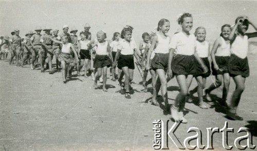 1945, Karaczi, Indie.
Zawody sportowe w obozie dla polskich uchodźców: defilada najmłodszych zawodników. [Polscy uchodźcy w 1942 trafili do Iran.u wraz z nowoutworzonym Wojskiem Polskim pod dowództwem generała Władysława Andersa (w dwóch rzutach ewakuacyjnych z ZSRR w marcu i sierpniu). W sumie oprócz wojska dotarło tam 38 tysięcy Polaków, z czego ponad połowę stanowiły dzieci i młodzież. Około 10 tysięcy z nich trafiła potem do Indii, m.in. do dwóch obozów przejściowych w Karaczi]
Fot. NN, zbiory Ośrodka KARTA, kolekcja Adeli Duszy przekazała Halina Guść