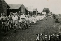 3.05.1946, Valivade, Indie.
Dzieci z koła ministrantów i Spółdzielni Zgoda uczestniczą w obchodach święta Konstytucji 3 maja. [Osiedle stałe w Valivade zostało wybudowane wiosną 1943 dla polskich uchodźców (głównie kobiet z dziećmi), którzy trafili do Iran.u wraz z nowoutworzonym Wojskiem Polskim pod dowództwem generała Władysława Andersa. Posiadało m.in. polską administrację samorządową, kościół, teatr, sklepy, cukiernie, szpitale, straż pożarną. W latach 1943–1947 przez osiedle przeszło około pięciu tysięcy Polaków].
Fot. NN, zbiory Ośrodka KARTA, kolekcja Adeli Duszy przekazała Halina Guść