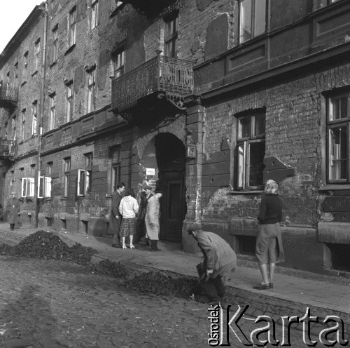 Lata 50., Warszawa, Polska.
Ul. Kępna - nabieranie węgla i rozmowa w bramie kamienicy.
Fot. Irena Jarosińska, zbiory Ośrodka KARTA