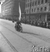 Lata 50., Warszawa, Polska.
Pochód pierwszomajowy w Alejach Jerozolimskich. Ulicą przejeżdża motocyklista z flagą.
Fot. Irena Jarosińska, zbiory Ośrodka KARTA