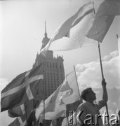 31.07.1955 - 4.08.1955, Warszawa, Polska.
V Światowy Festiwal Młodzieży i Studentów o Pokój i Przyjaźń. Flagi i uczestnik festiwalu na tle Pałacu Kultury i Nauki.
Fot. Irena Jarosińska, zbiory Ośrodka KARTA