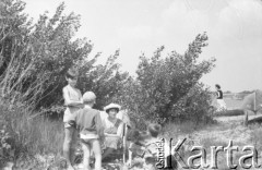 Koniec lat 50., Warszawa, Polska.
Dzieci bawią się nad brzegiem Wisły, koło nich siedzi kobieta na krześle turystycznym. 
Fot. Irena Jarosińska, zbiory Ośrodka KARTA