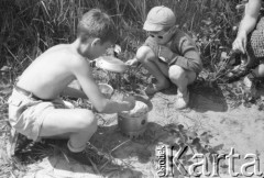 Koniec lat 50., Warszawa, Polska.
Wypoczynek nad brzegiem Wisły. Dzieci gotują w małej kuchence turystycznej.
Fot. Irena Jarosińska, zbiory Ośrodka KARTA 
