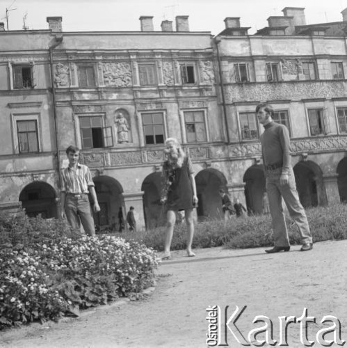 1968, Zamość, woj. lubelskie, Polska.
Kobieta i dwóch mężczyzn pozuje do zdjęcia na tle kamienic z podcieniami na Rynku Wielkim.
Fot. Irena Jarosińska, zbiory Ośrodka KARTA