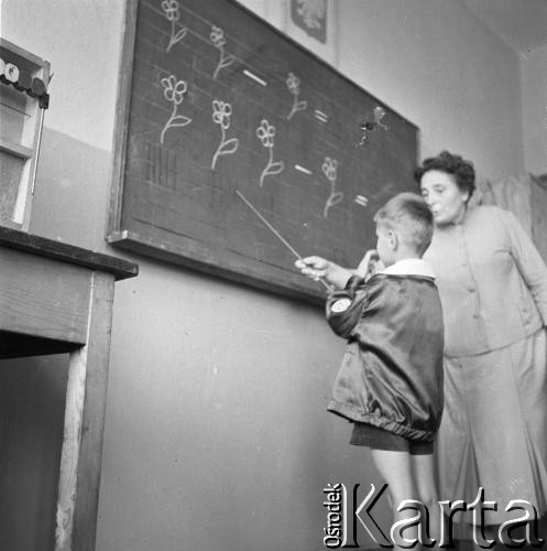 1961, Wrocław, Polska.
Lekcja w szkole podstawowej nr 70. Nauczycielka i jeden z czworaczków braci Majewskich przed tablicą.
Fot. Irena Jarosińska, zbiory Ośrodka KARTA