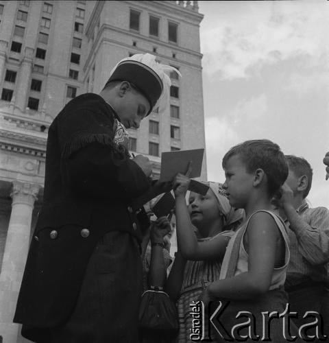 31.07.1955 - 4.08.1955, Warszawa, Polska.
V Światowy Festiwal Młodzieży i Studentów o Pokój i Przyjaźń. Górnik podpisuje się w notesach dzieci. W głębi widać Pałac Kultury i Nauki. 
Fot. Irena Jarosińska, zbiory Ośrodka KARTA