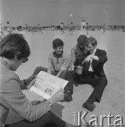 22-25.08.1968, Sopot, Polska.
Międzynarodowy Festiwal Piosenki w Sopocie. Członkowie zespołu Czerwone Gitary na plaży. Krzysztof Klenczon czyta odwróconą do góry nogami gazetę, naprzeciwko niego od lewej Bernard Dornowski, Seweryn Krajewski i Jerzy Skrzypczyk.
Fot. Irena Jarosińska, zbiory Ośrodka KARTA

