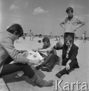 22-25.08.1968, Sopot, Polska.
Międzynarodowy Festiwal Piosenki w Sopocie. Członkowie zespołu Czerwone Gitary na plaży. Krzysztof Klenczon czyta gazetę, naprzeciwko niego od lewej Bernard Dornowski, Seweryn Krajewski (stoi) i Jerzy Skrzypczyk.
Fot. Irena Jarosińska, zbiory Ośrodka KARTA

