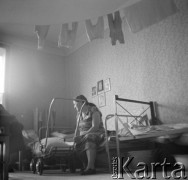 1950-1960, Nowa Huta, Kraków, Polska.
Matka z dzieckiem w wózku w pokoju hotelu robotniczego. Na pierwszym planie podwieszone pod sufitem suszące się dziecięce ubranka. Prawdopodobnie to wnętrze jednego z hoteli dla samotnych matek.  
Fot. Irena Jarosińska, zbiory Ośrodka KARTA