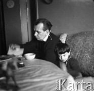 Lata 60., Polska.
Mężczyzna z dzieckiem przy stole. Na pierwszym planie na stole widoczne dzięcięce zabawki.
Fot. Irena Jarosińska, zbiory Ośrodka KARTA