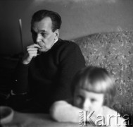 Lata 60., Polska.
Mężczyzna z dzieckiem przy stole. 
Fot. Irena Jarosińska, zbiory Ośrodka KARTA