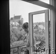 Lata 50., Kazimierz Dolny, Polska.
Kobieta na balkonie. W tle Kościół farny św. Jana Chrzciciela i św. Bartłomieja.
Fot. Irena Jarosińska, zbiory Ośrodka KARTA